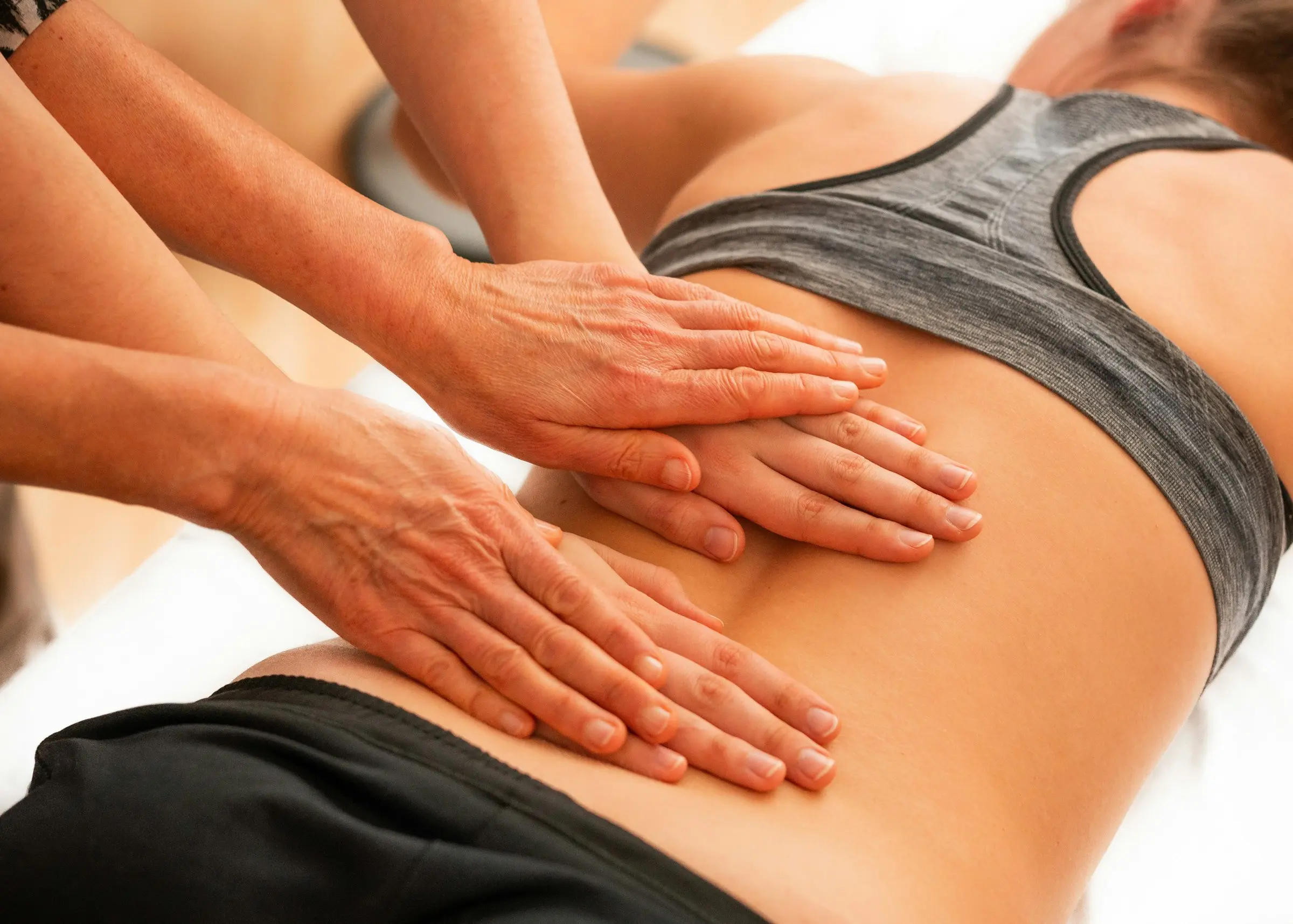 An osteopathic treatment: hands working on a patient's lower back